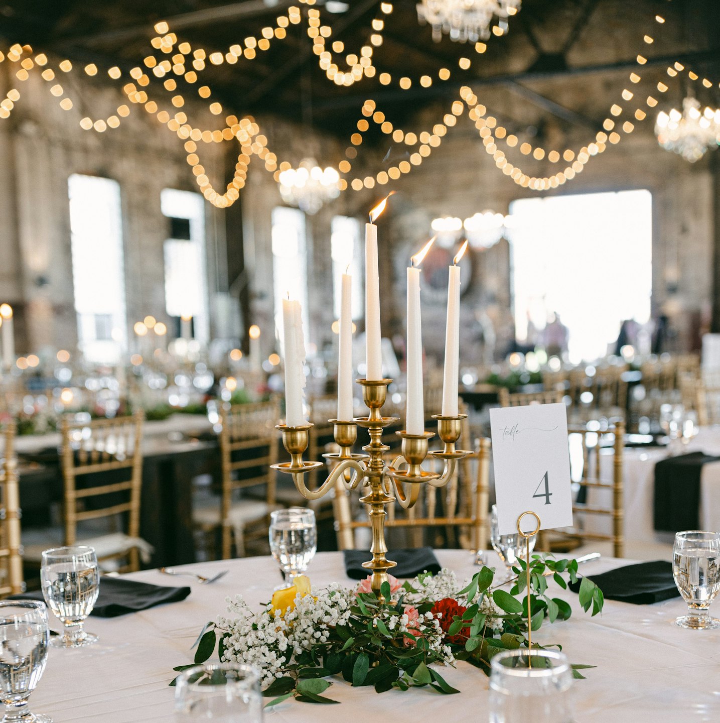 Elegante tavolo da evento con candelabro dorato e centrotavola floreale.