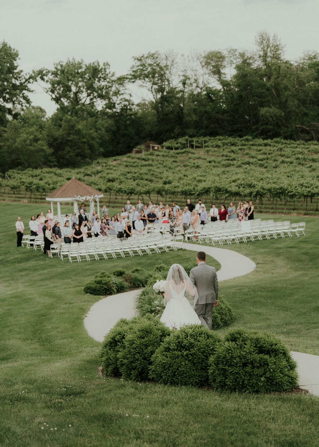 Una sposa e uno sposo camminano insieme verso un matrimonio all'aperto.